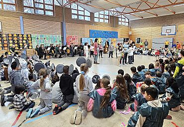 Schulkinder sitzen mit dem Ensemble der Bremer Philharmoniker im Kreis in der Sporthalle und verfolgen eine Aufführung einer Kindergruppe, die in der Kreismitte steht.