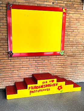 gelb-rote Friedenstreppe vor einer Mauer