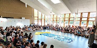 Kinder und Erwachsenen sitzen im Kreis auf dem Fußboden