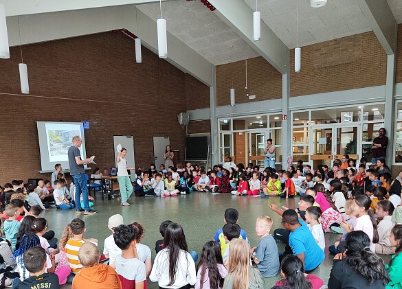 Kinder und Erwachsene treffen sich zum Plenum in der Aula 