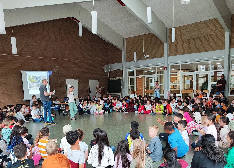 Kinder und Erwachsene treffen sich zum Plenum in der Aula 