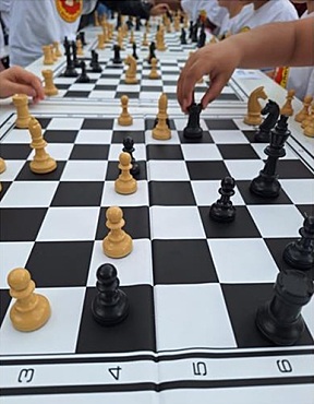 Ein Bild, das Kinderhände, Schachbretter und Schachfiguren zeigt.