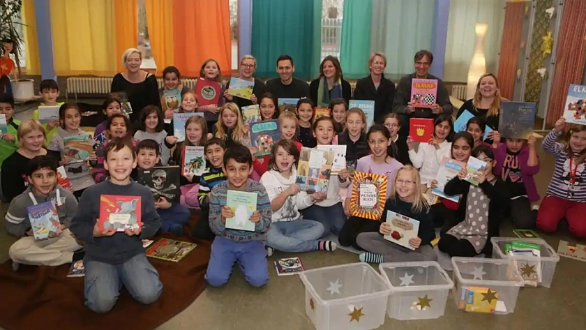 Kinder zeigen ihre Bücher, die sie beim Picknick gelesen haben 